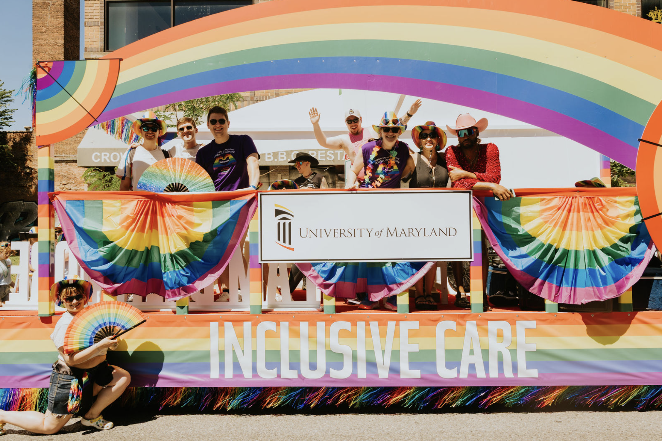 People posing on the UMSOM and UMMC Pride float wearing colorful, rainbow clothing at the 2026 Baltimore Pride Parade.